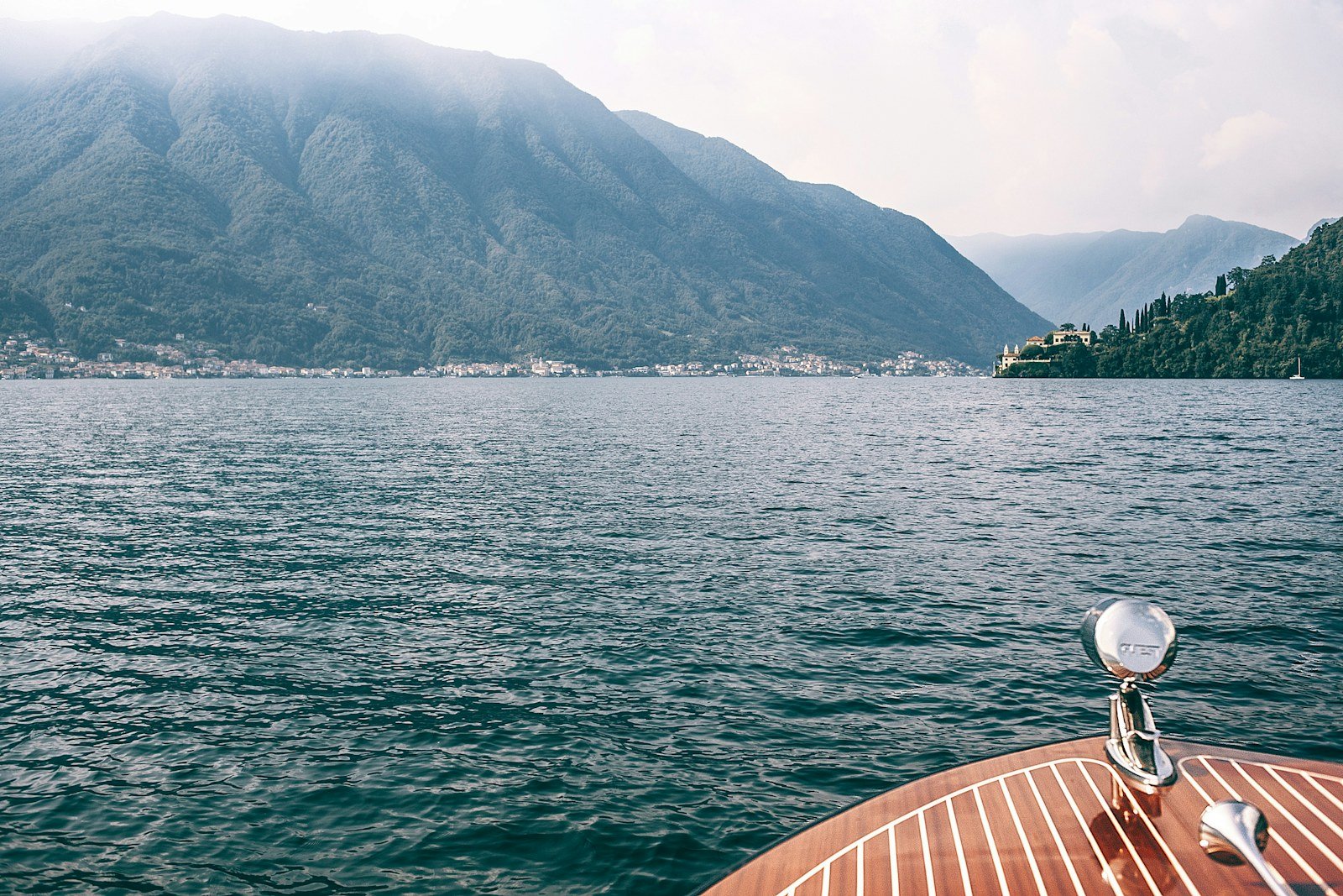 A boat moored on Lake Como with misty mountains in the background